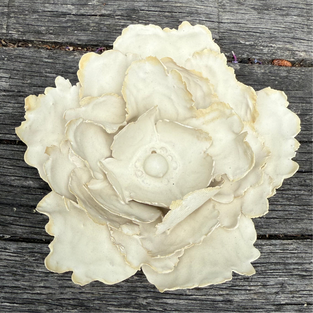 White ceramic flower on wood background