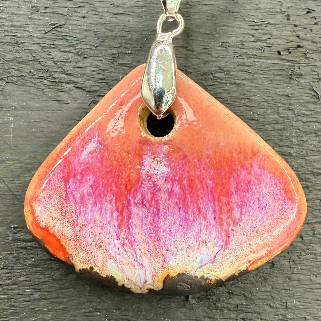 Pendant with pink and orange triangular stone on a dark surface