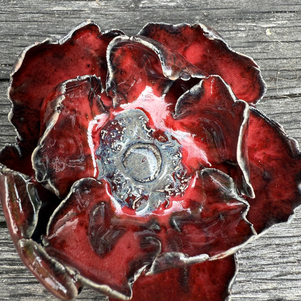 Red ceramic handmade poppy on wood background
