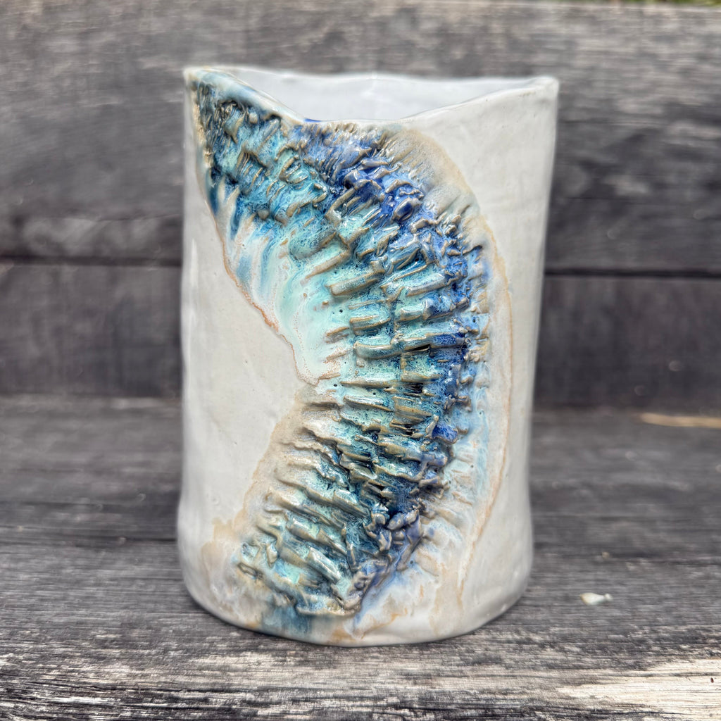Ceramic vase with textured blue design on a wooden surface