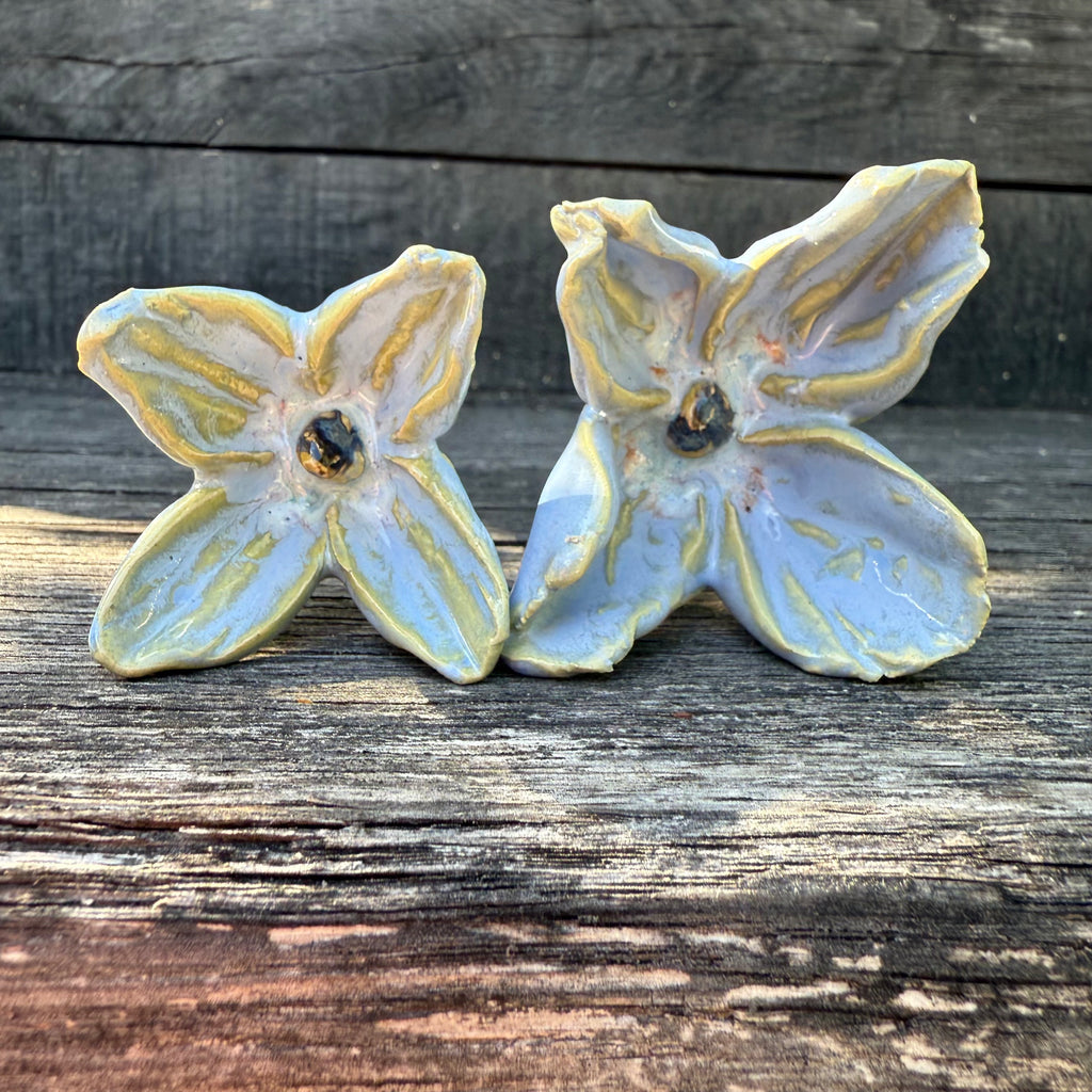 Two ceramic flowers with stems  on a wooden surface