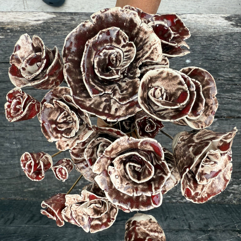 Bouquet of brown and red ceramic flowers on a dark wooden surface