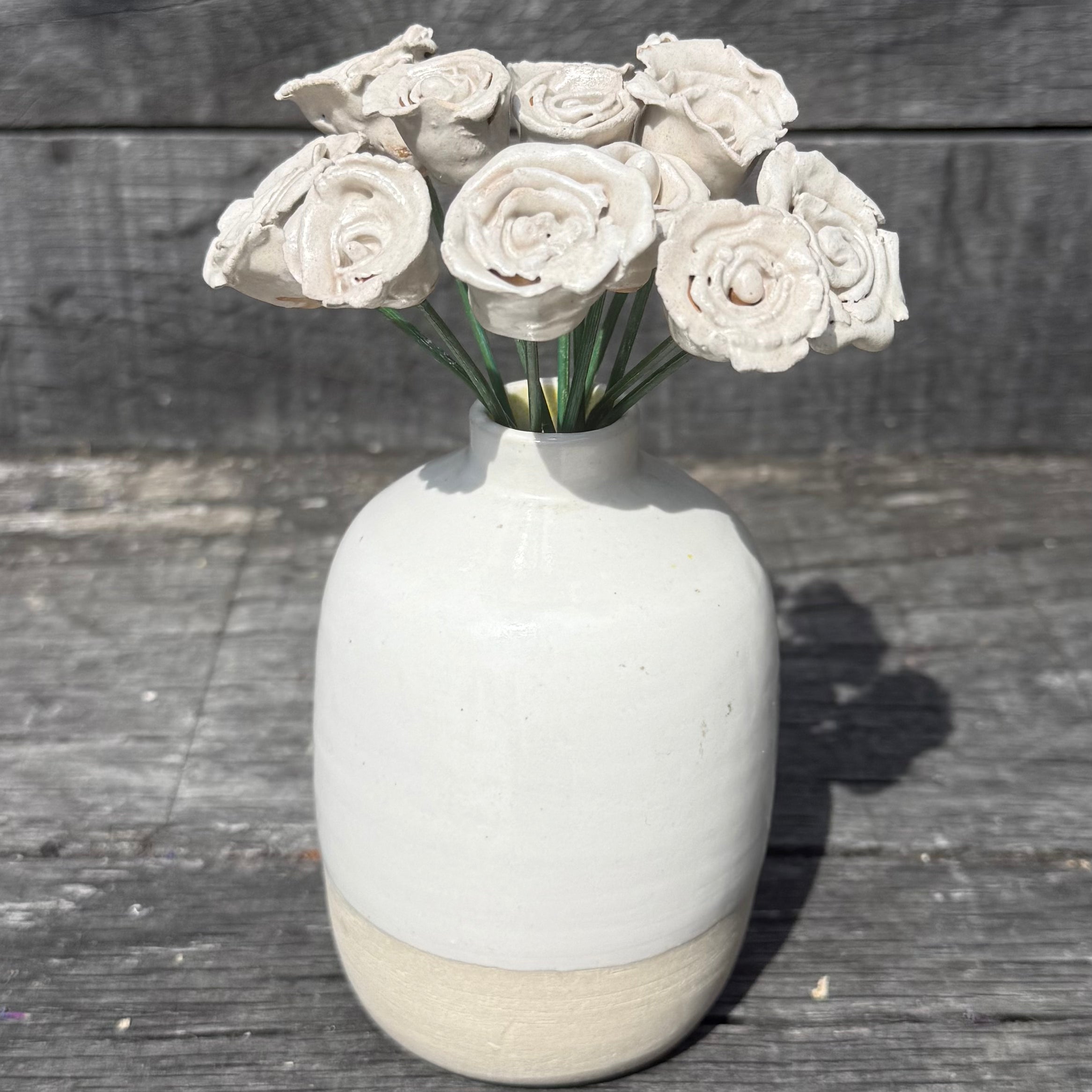 White ceramic vase with decorative flowers on a wooden surface