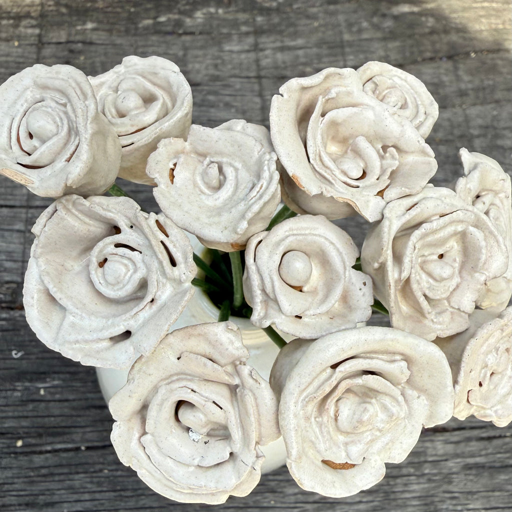 White ceramic roses arranged in a circular pattern on a wooden surface