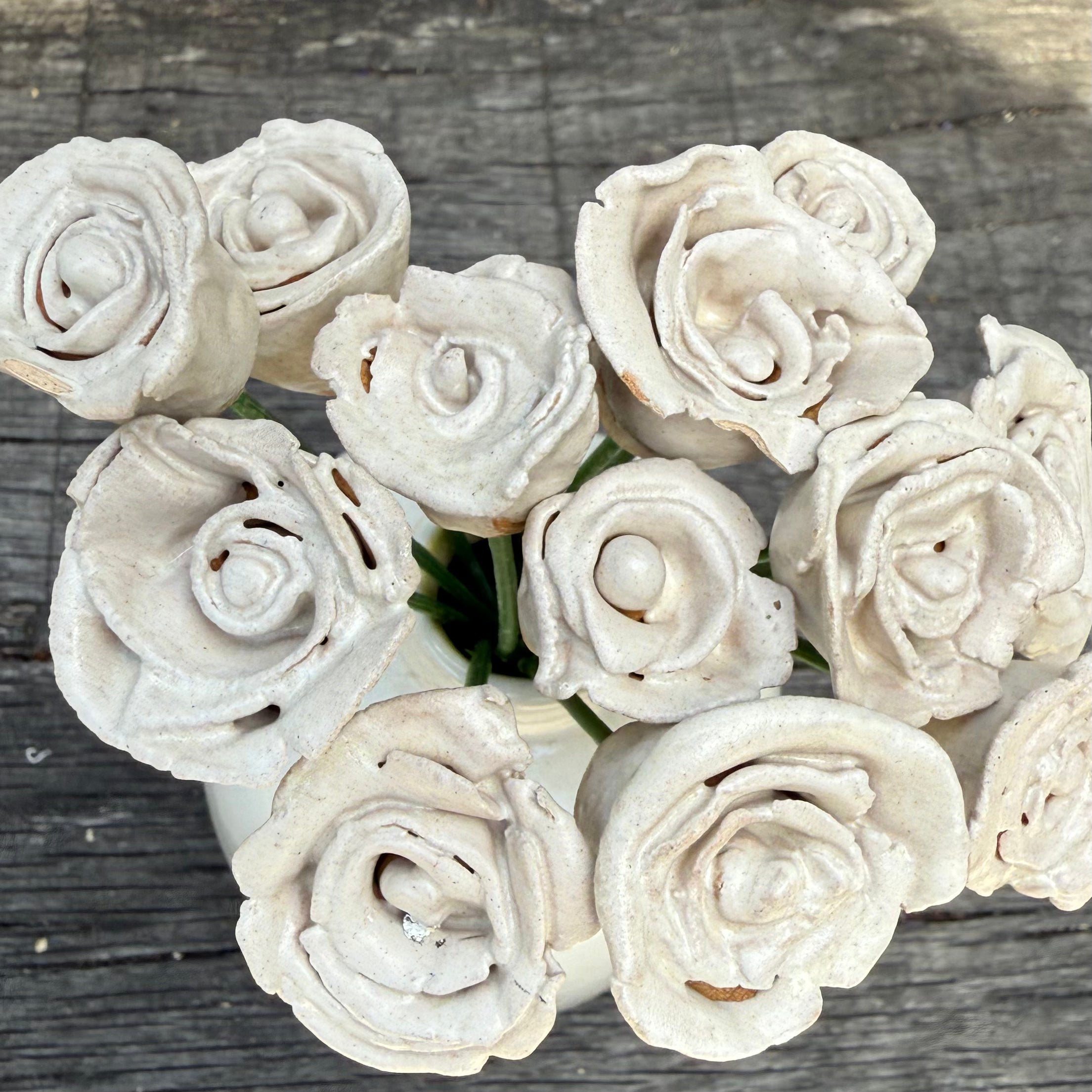 White ceramic roses arranged in a circular pattern on a wooden surface